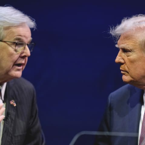 Dan Patrick, left, shaking hands with and talks to Donald Trump on stage.