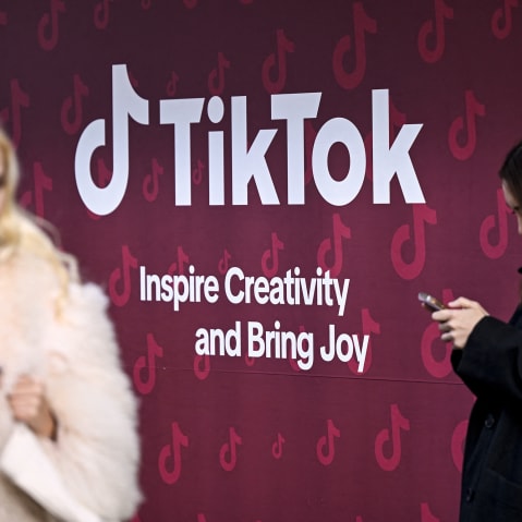Women use their phones in front of TikTok's booth during the World Economic Forum in Davos, Switzerland.