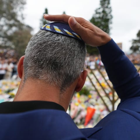 A man touches his kippah during a menorah lighting ceremony at a floral memorial for victims of the Bondi Beach shooting on Dec. 16, 2025 in Sydney, Australia.