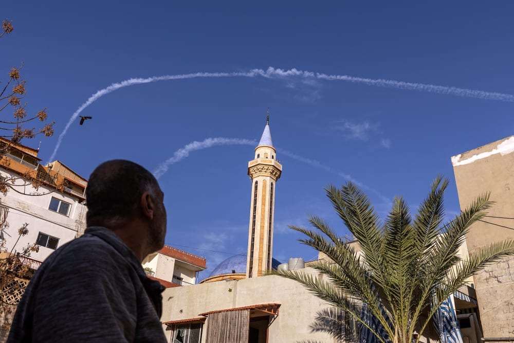A Lebanese man watches contrails from IDF fighter jets in the sky over Tyre, Lebanon.