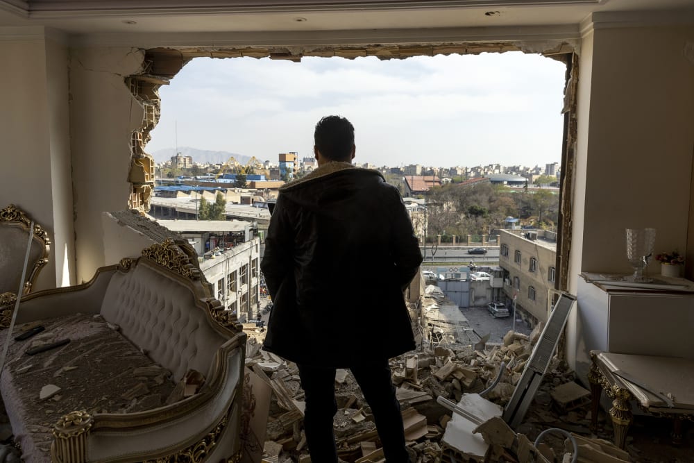 A man stands in a damaged residence after an airstrike.