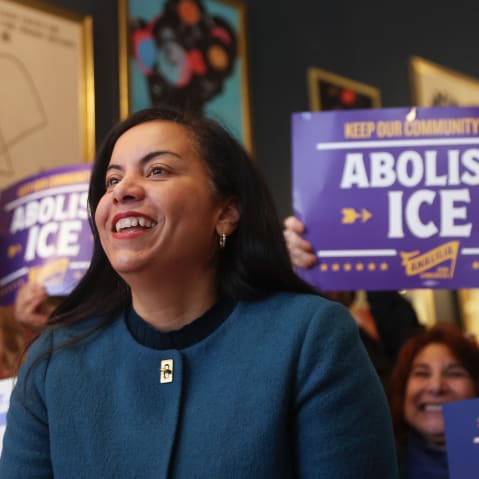 Analilia Mejia. People behind her hold signs in support.
