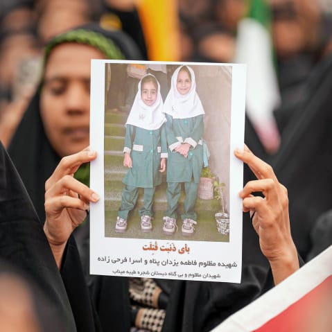 Mourners hold a portrait of a students during a funeral ceremony for children who were killed after a primary school was targeted in US and Israeli attacks in Minab, Iran.