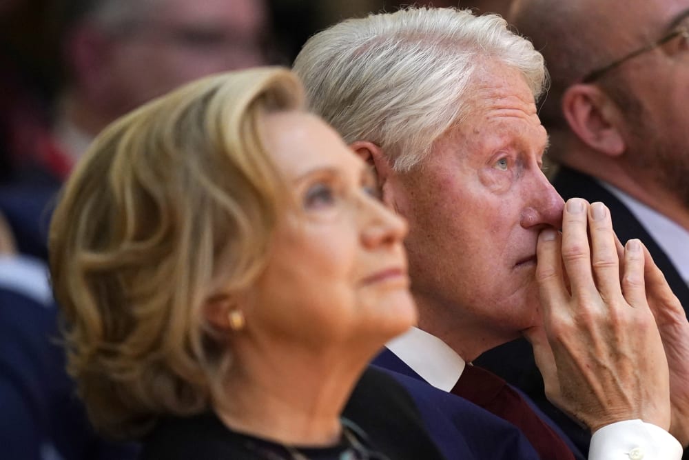 Hillary Clinton, left, looks up as she sits next to her husband Bill Clinton.