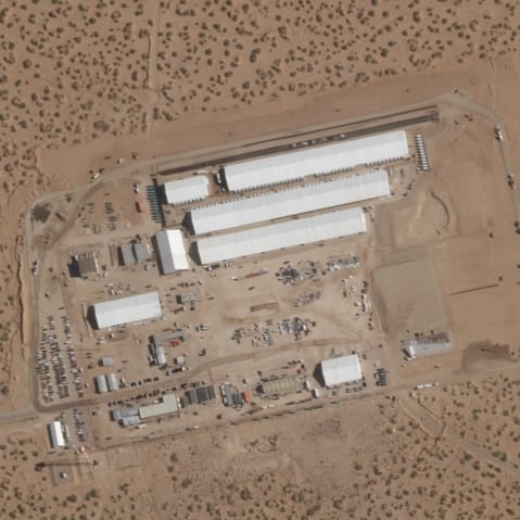 An aerial satellite image showing white tents in the middle of a desert.