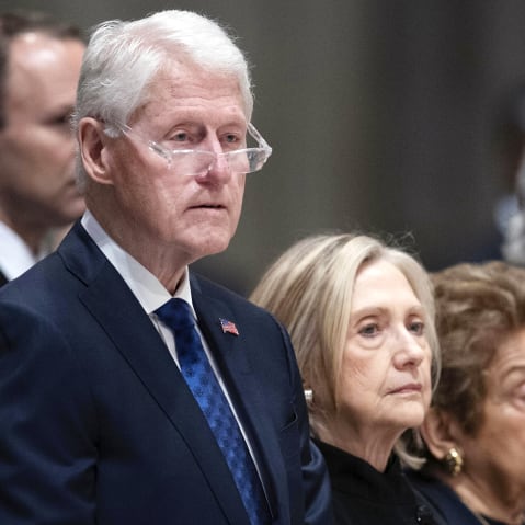 Bill and Hillary Clinton stand in the pews of the National Cathedral.