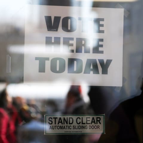 A Vote Here sign seen on a window.