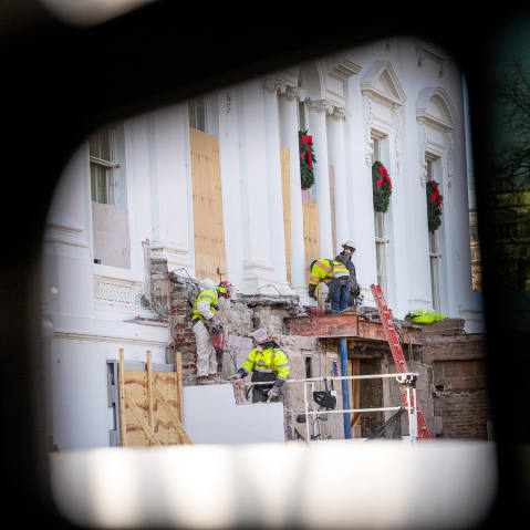 Construction workers take down material where the East Wing used to connect to the White House.