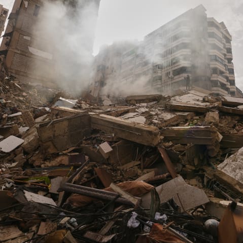 A man stands atop the rubble of a building destroyed in an Israeli airstrike near Beirut