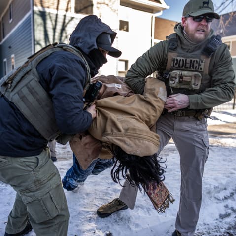 Two agents are carrying a person as they arrest them.