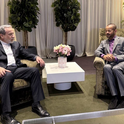 Abbas Araghchi, left, speaks to Badr Albusaidi as they sit side by side at arm chairs.