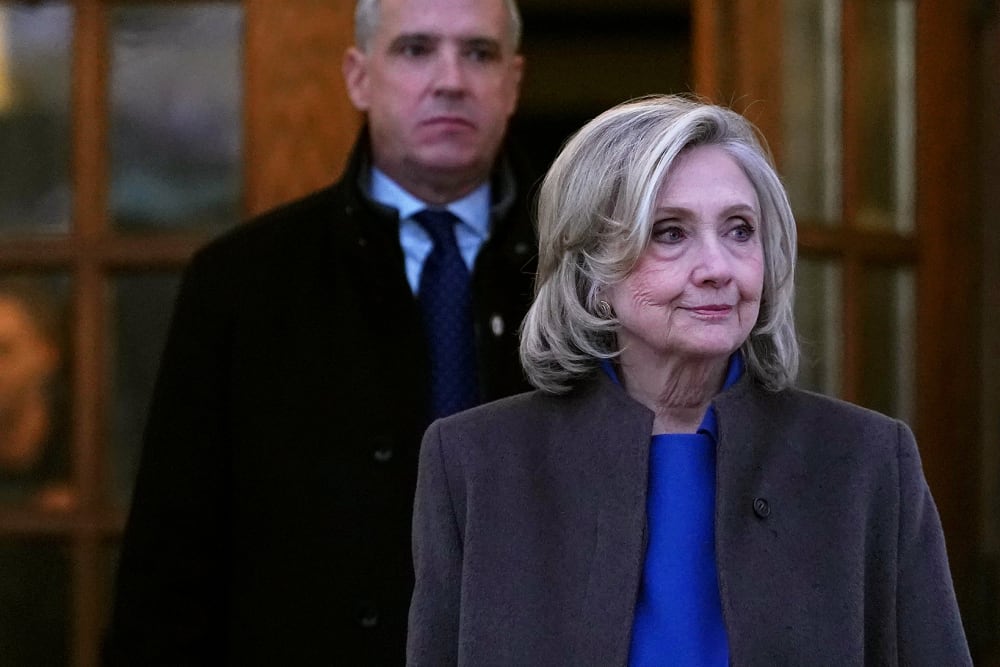 Hillary Clinton, right, looks off while walking out from a double set of doors.