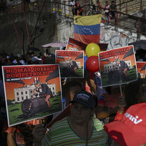 Supporters of Venezuelan President Nicolas Maduro show signs that reads in spanish "No more war for oil, the world demands it."