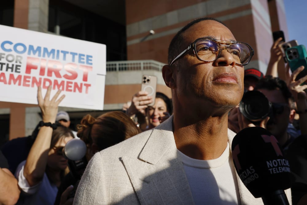 Don Lemon looks on as people protest behind him.