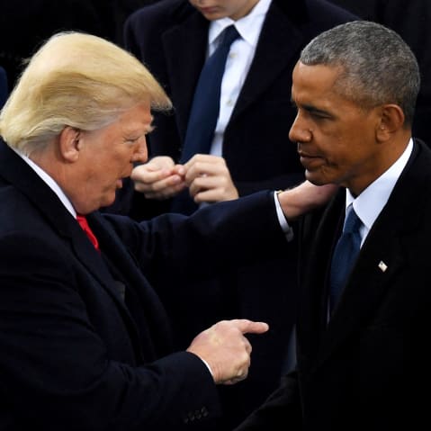Donald Trump holds Barack Obama' shoulder while pointing at him with his other hand.