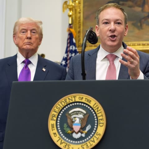 Donald Trump, left, and Lee Zeldin, who speaks into a microphone at a podium.