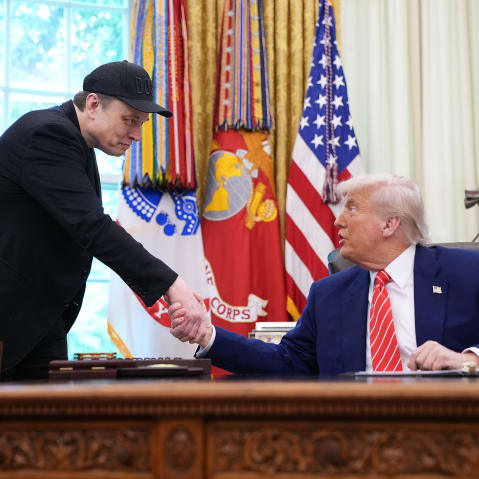 Elon Musk, left, and President Donald Trump shake hands in the Oval Office