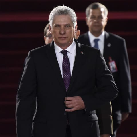 Miguel Díaz-Canel walks toward the camera with his hand on his suit jacket's button.