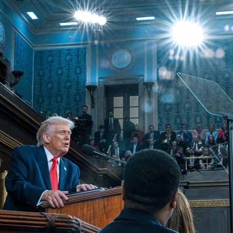 Bright lights shine on Donald Trump as he speaks at a podium.
