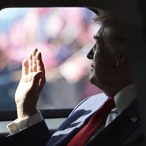 President Donald Trump waves from his official vehicle as he departs from Kuala Lumpur International Airport.