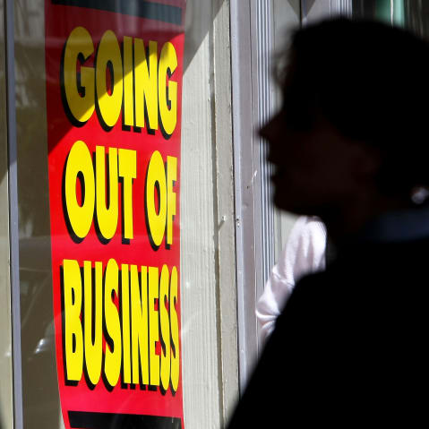 A pedestrian walks by a sign announcing a going out of business sale in California.