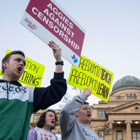People hold signs calling for an end to censorship at Texas A&M's campus.