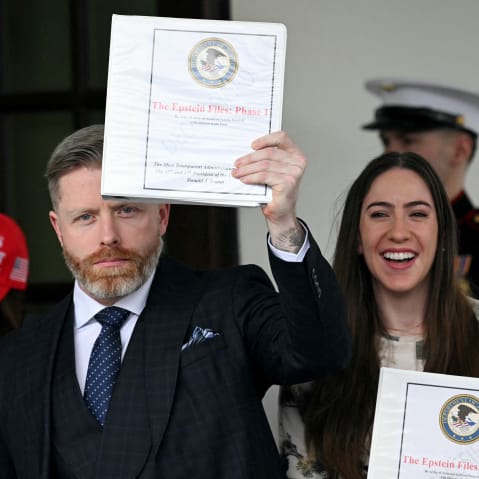 Three people cary Epstein binders, one of them is holdinhg it up.