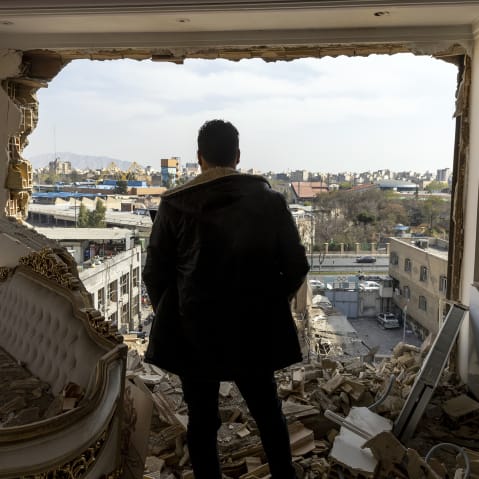 A man stands in a damaged residence after an airstrike.