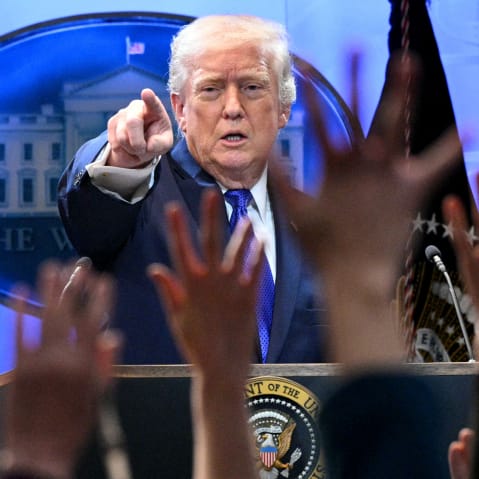 Donald Trump points at a press member as they raise their hands to ask questions.
