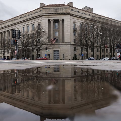 The Department of Justice building, seen reflected in a puddle.