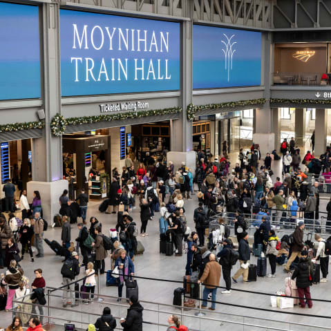 Passengers wait in the grand hall at Penn station in this wide frame shot from above.