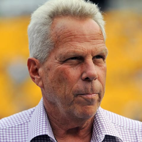 Steve Tisch is seen looking away in this closeup shot in front of a yellow background.