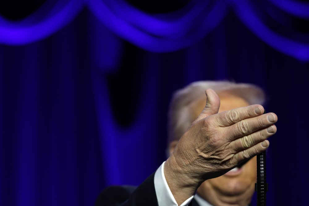 Donanld Trump's right hand obscures his face as he speaks at the National Prayer.