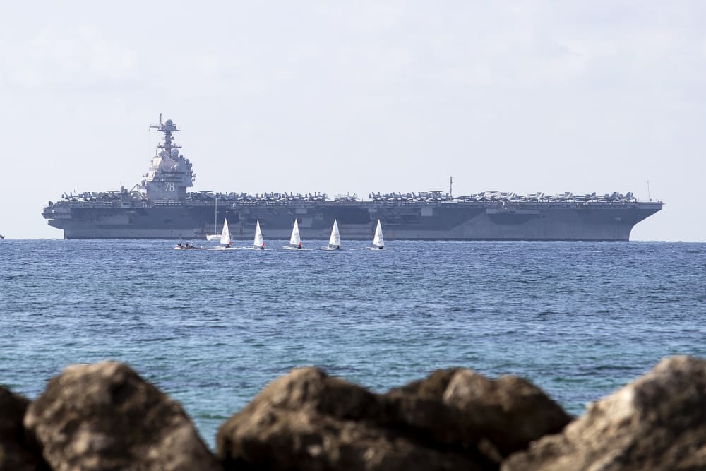 USS Gerald Ford ship is seen in the distance in the ocean.