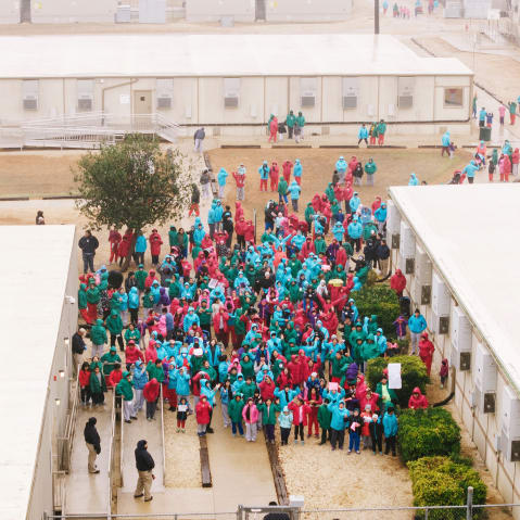 In this aerial shot, people are seen gathering in an immigration facility.