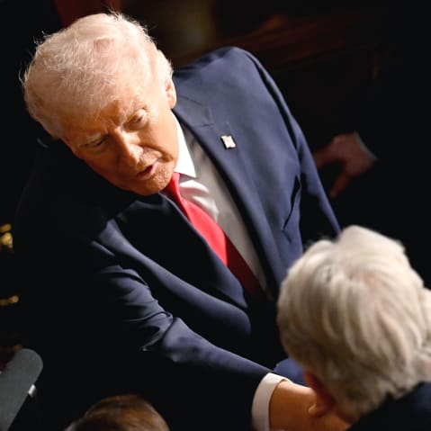 Donald Trump shakes hands with a man in this tilted frame shot from above.