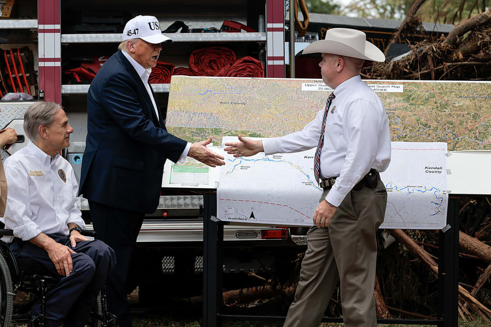 Donald Trump shakes hands with an official at the disaster scene after the deadly flooding in the area.
