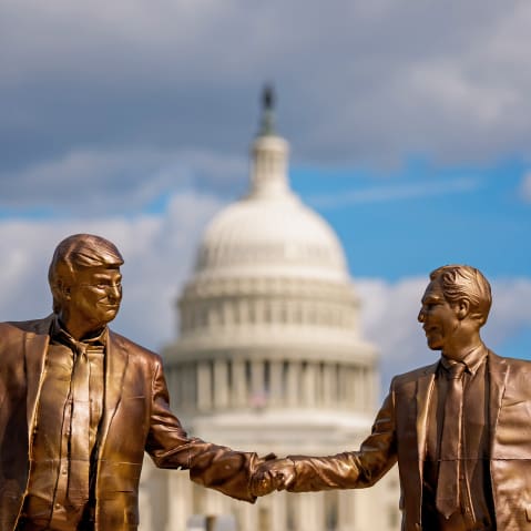A golden statue depicts Donald Trump, left, and Jeffrey Epstein holding hands. In the background, the Capitol is out of focus.