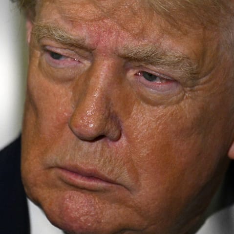 A close-up photo of Present Trump's face while he talks to reporters on Air Force One.