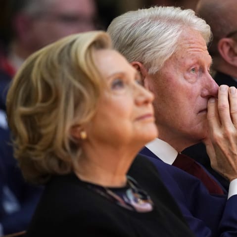 Hillary Clinton, left, looks up as she sits next to her husband Bill Clinton.