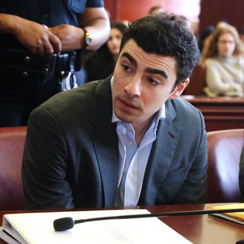 Luigi Mangione talks to a man as he sits in the court room.