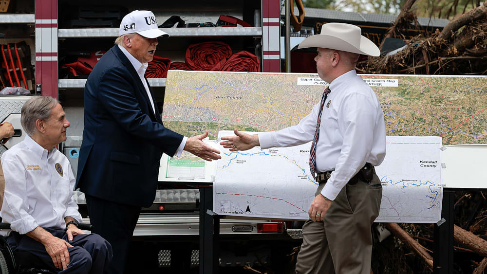 Donald Trump shakes hands with an official at the disaster scene after the deadly flooding in the area.