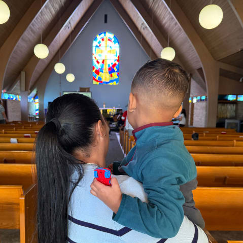 A woman holds a young child in a church