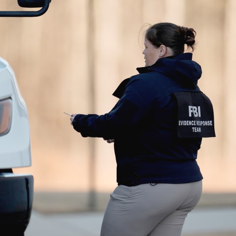 A female FBI officer stands near a white truck. Back of her jacket reads "FBI Evidence Response Team."