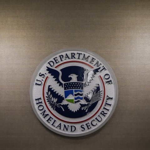 DHS logo is seen on a wall along with two light fixtures on both sides of it.