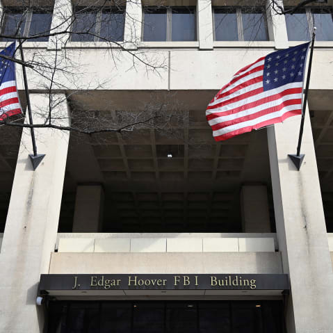 FBI headquarters sign is seen between two American flags.