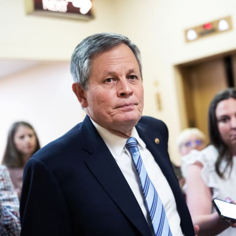 Steve Daniels walks in the direction of the camera as journalists follow him asking questions.