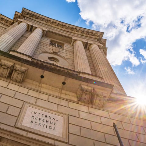 The sun flairs over the side of the IRS headquarters building.