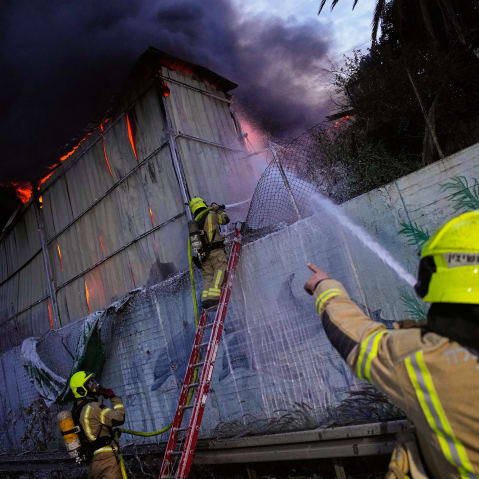 Firefighters try to extinguish flames at the site of a direct hit by an Iranian missile.