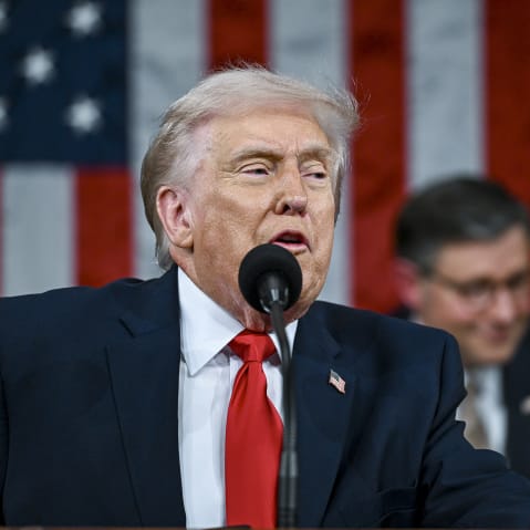 Trump speaking with JD Vance and Mike Johnson standing behind him